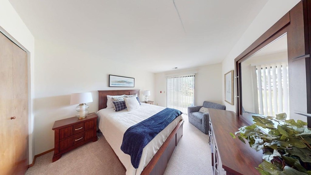 A bedroom with a bed, nightstand, and chair.