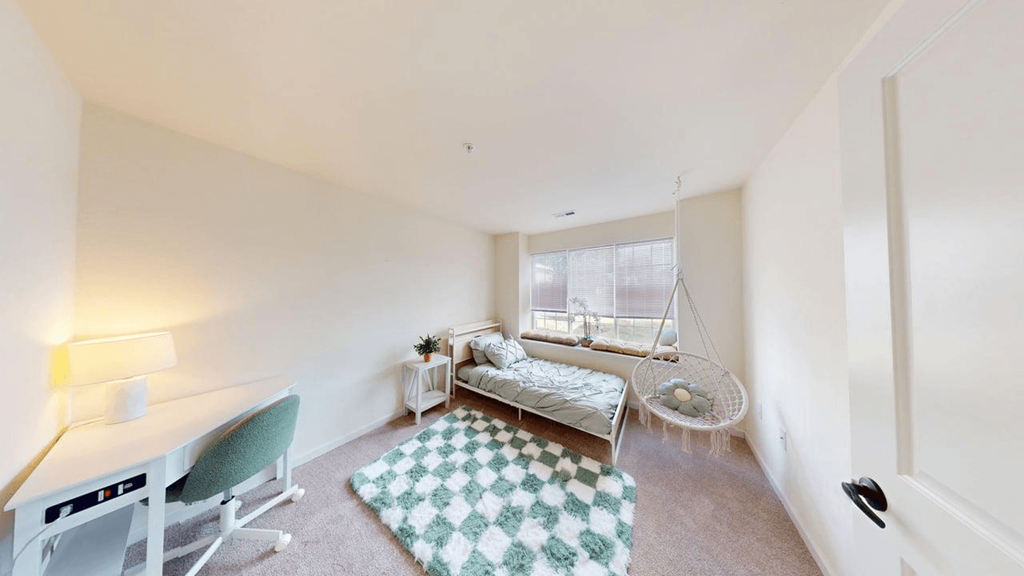 A white room with a green chair and a hanging swing.