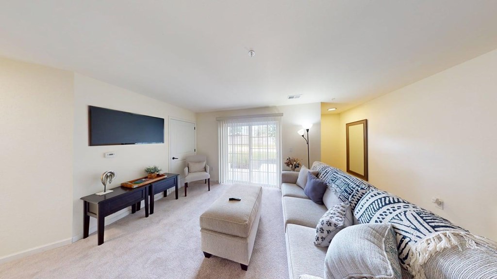 A living room with a grey couch and a television on the wall.