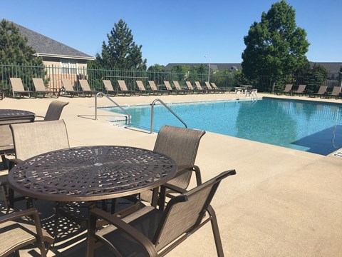 A poolside table and chairs overlook a swimming pool.