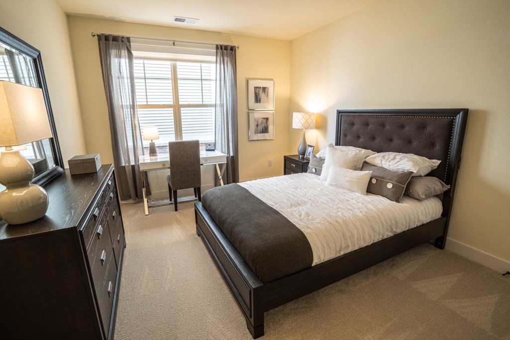 a bedroom with a bed and a desk and a window