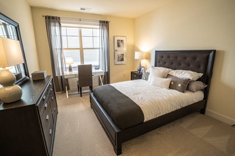 a bedroom with a bed and a desk and a window