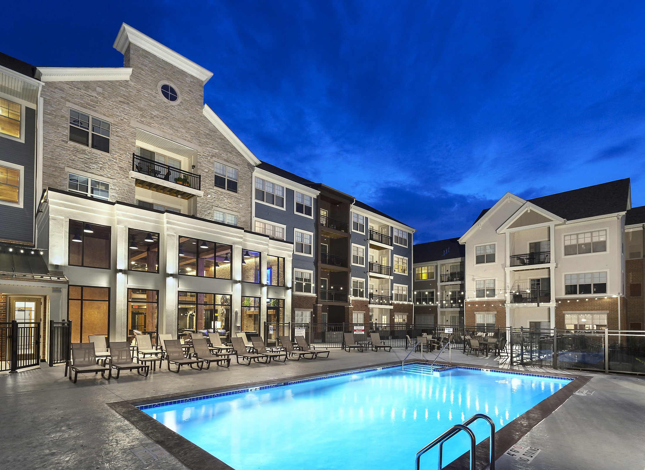 a swimming pool in front of an apartment building at night