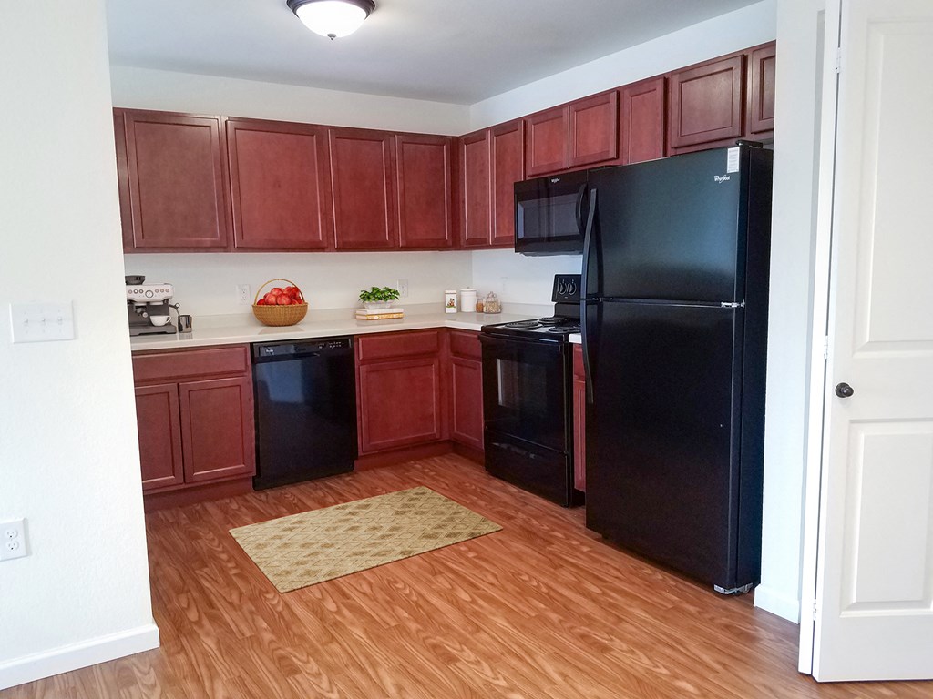 an empty kitchen with black appliances and wood flooring