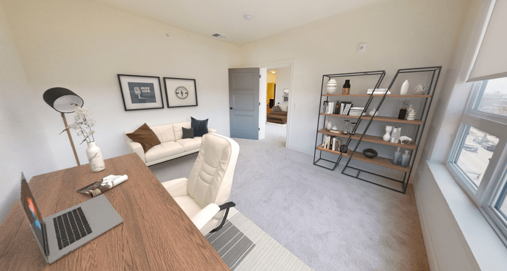 a living room with a couch and a desk with a laptop