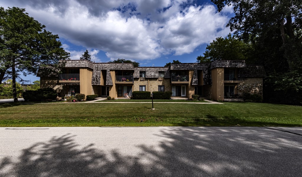 an apartment building with a lawn and a cloudy sky