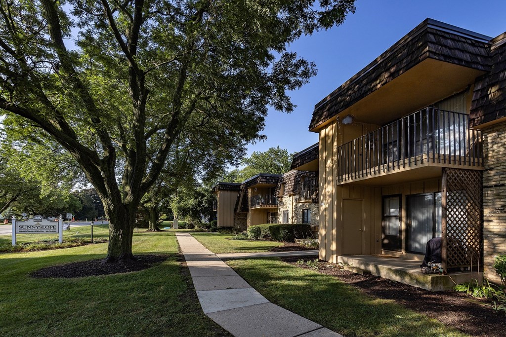 apartments with a sidewalk and trees in front of a building