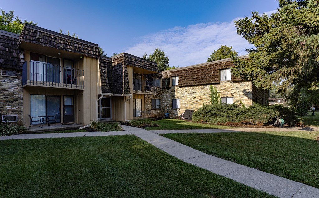 a view of two apartment buildings with grass and a sidewalk