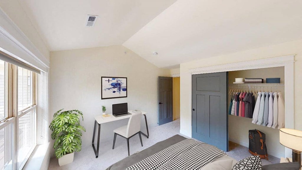 a bedroom with a bed and a desk with a laptop