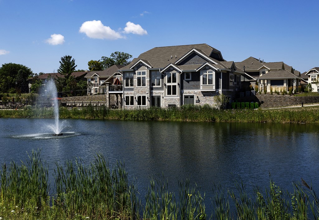 a pond with a fountain in front of a house
