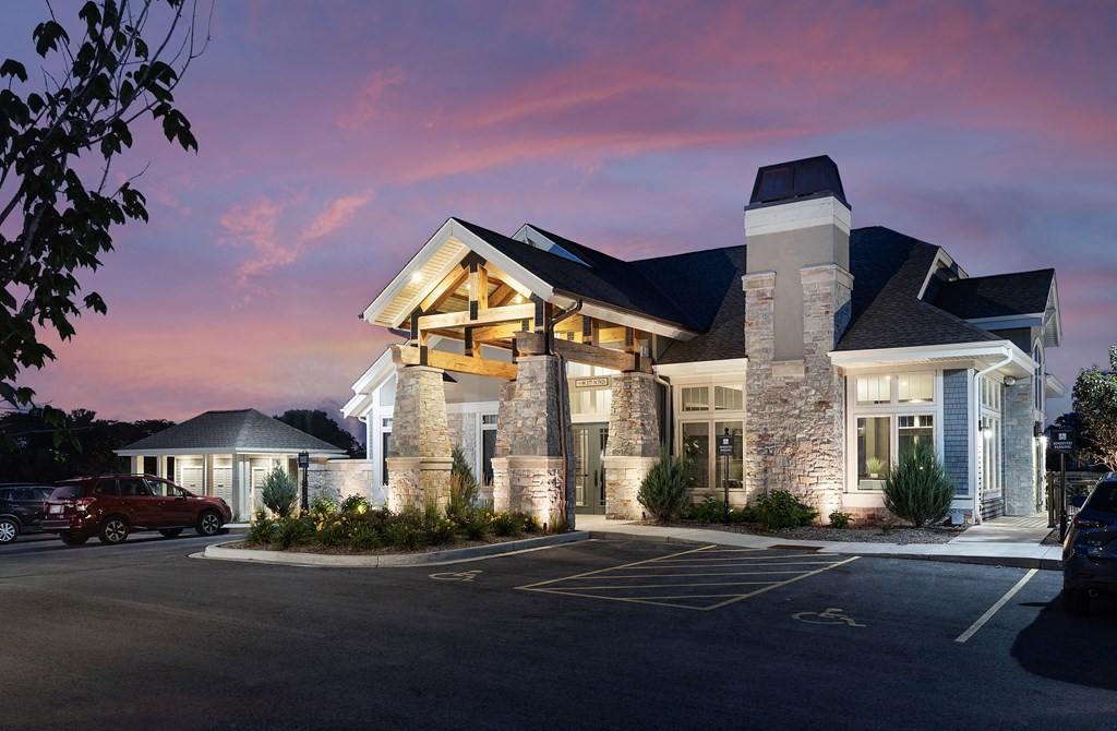the facade of a hotel at sunset with a parking lot