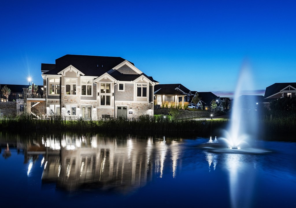 a fountain in a pond in front of a house