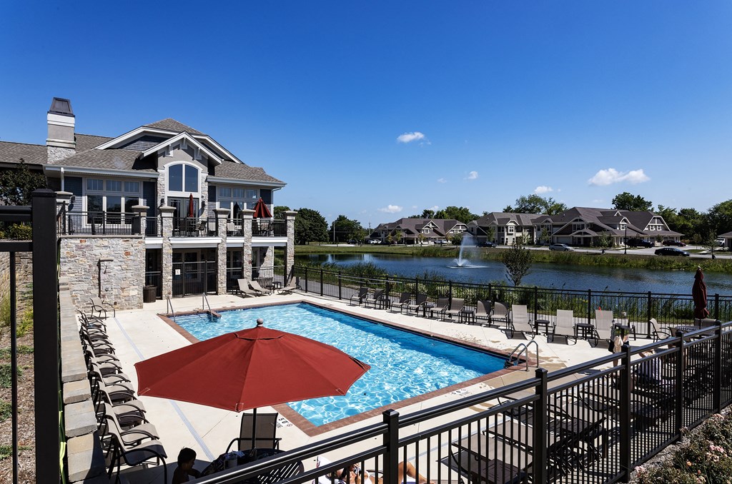 a pool with a red umbrella in front of a house