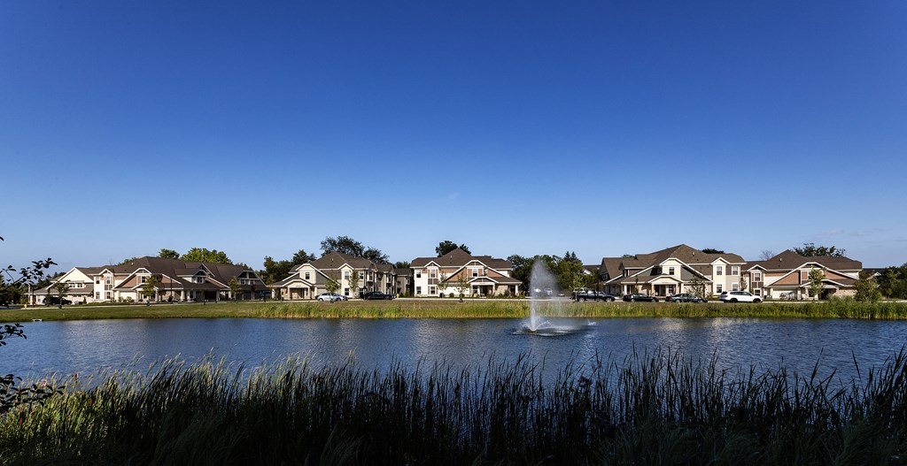 a fountain in a pond with houses in the background