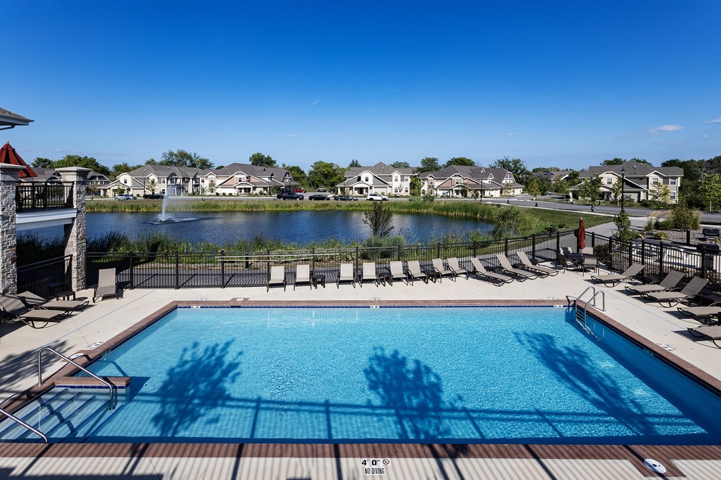 an aerial view of a swimming pool with a lake and houses in the background