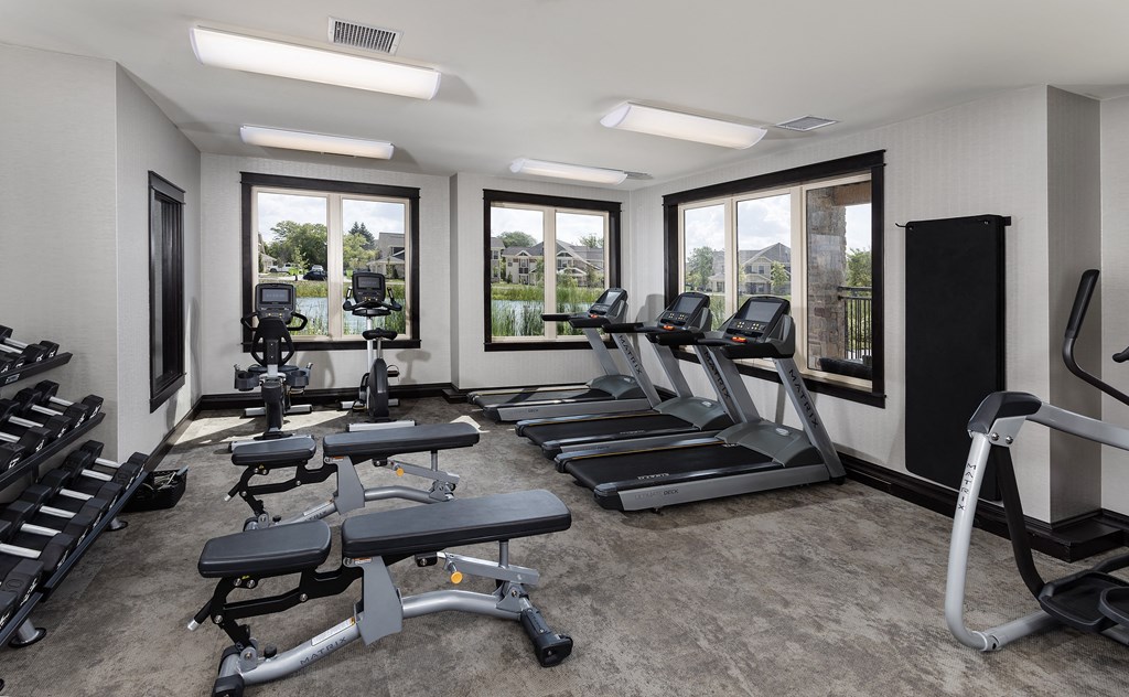 a gym with cardio equipment and windows in a building
