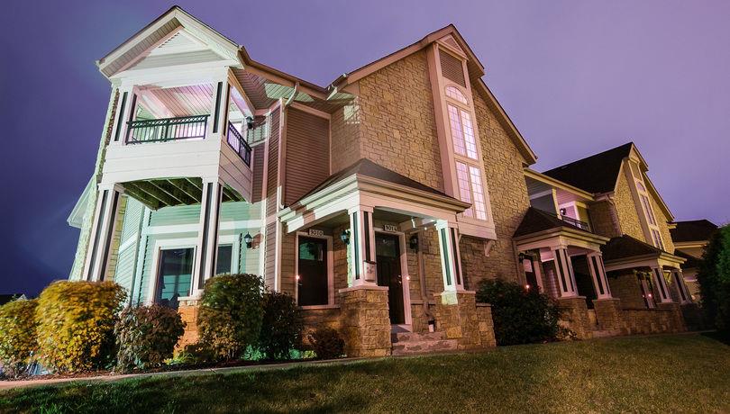 a brick house with a green porch and a purple sky