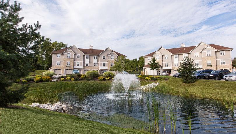 a pond with a fountain in front of some apartments