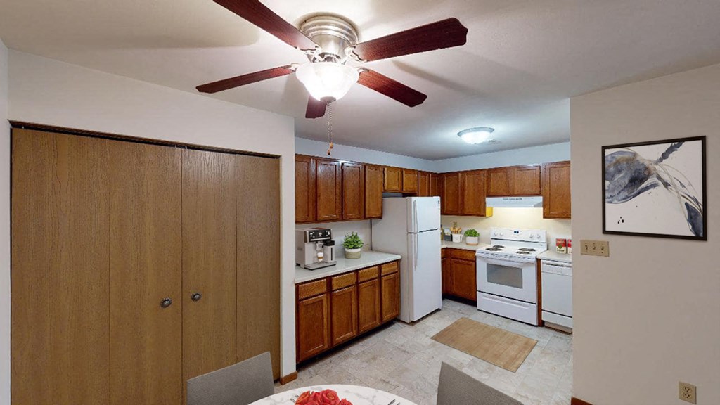 a kitchen with white appliances and a ceiling fan