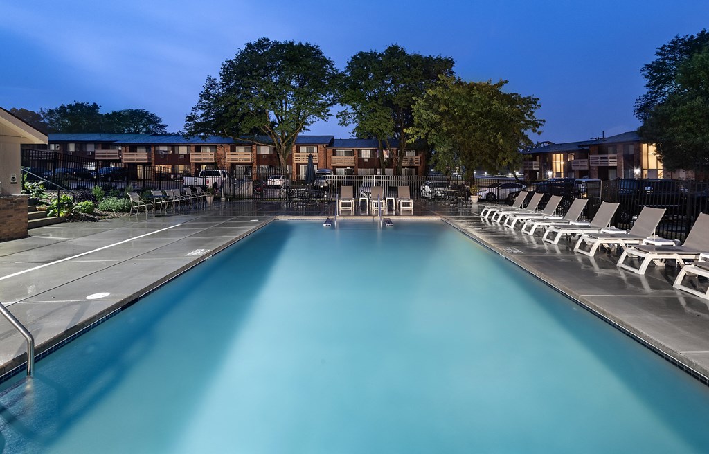 a swimming pool at night with chairs around it