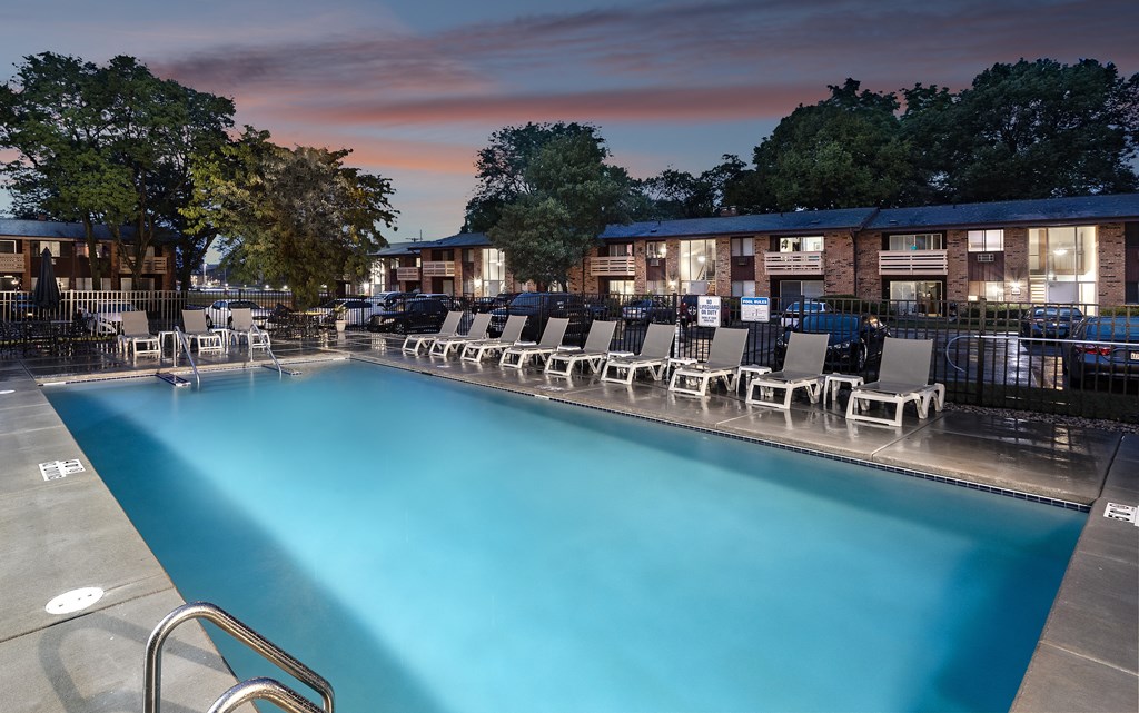 a swimming pool with chairs at dusk
