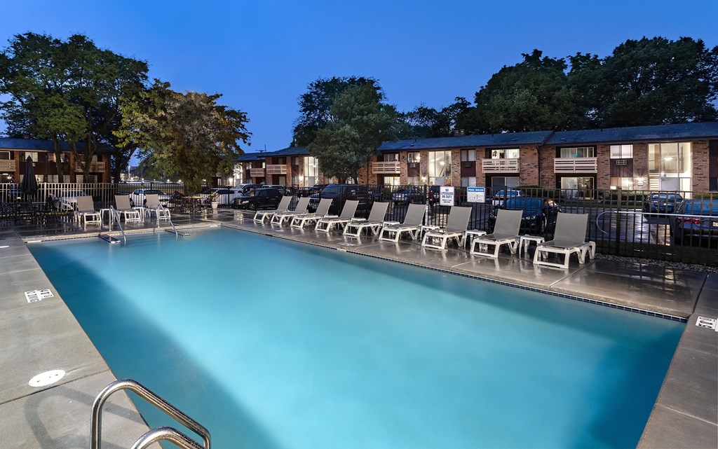 a swimming pool with chairs at night