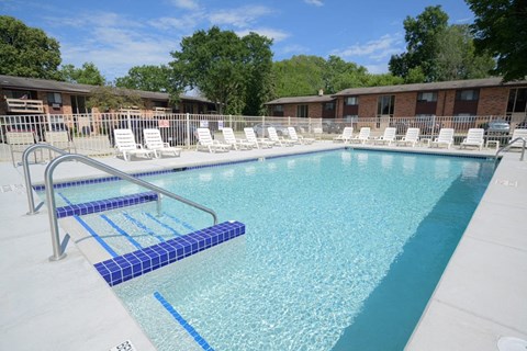 a large pool with white chairs and a fence around it