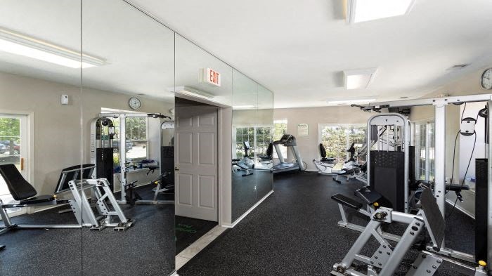 a gym with weights and mirrors and a door