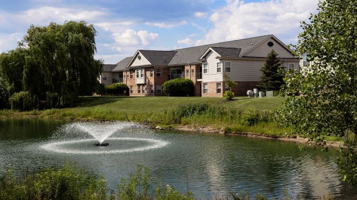 a fountain in a pond in front of a house