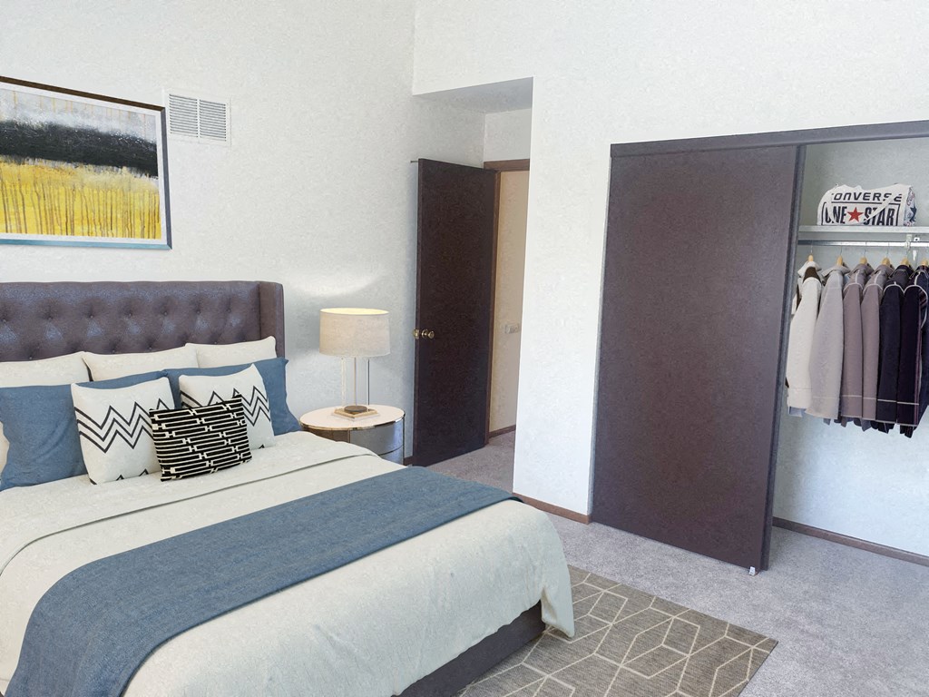 a bedroom with a bed and a closet with clothes hanging in it