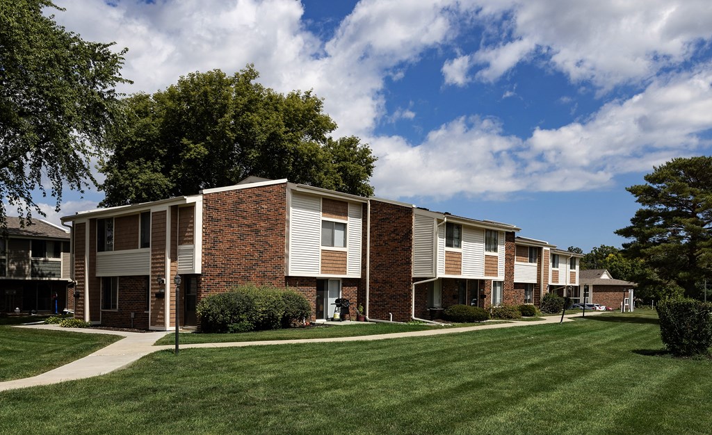 a row of apartment buildings with lawns and trees