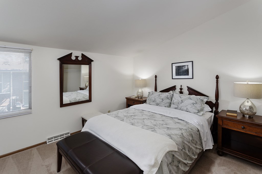 a bedroom with a large bed and a mirror on the wall