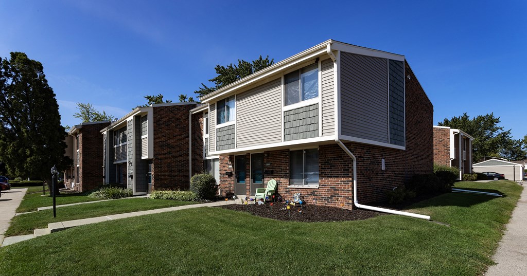 a brick apartment building with a lawn and a sidewalk