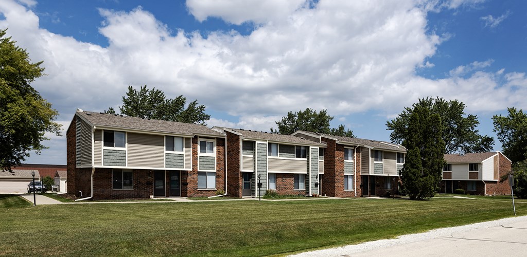 a row of apartment buildings with grass and trees