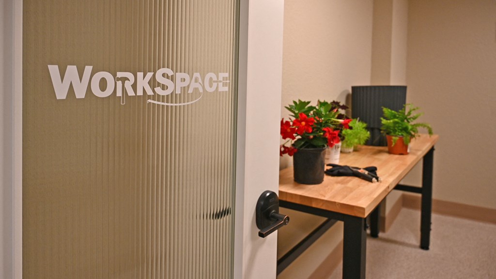 a door with the words workspace on it and a table with plants on it