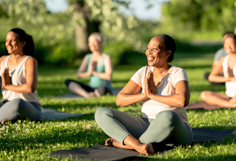 a group of women practicing yoga in the park