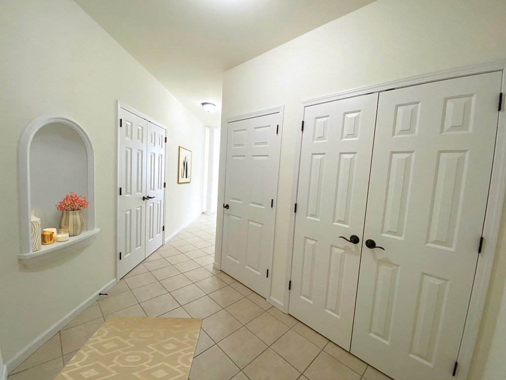 a hallway with white closets and doors and a tiled floor