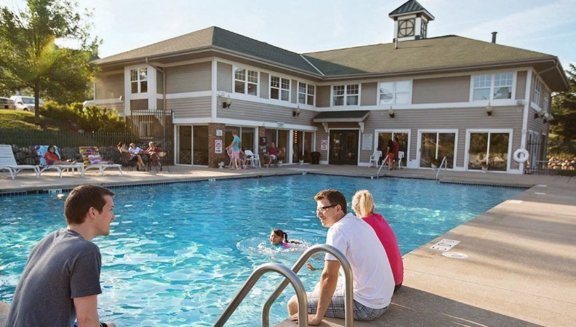 a group of people sitting at a pool with a building in the background