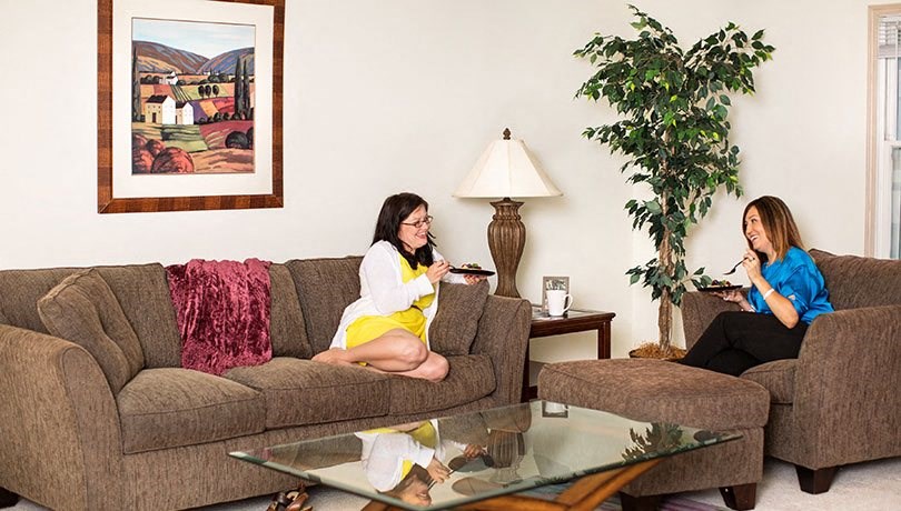 two women sitting on a couch in a living room