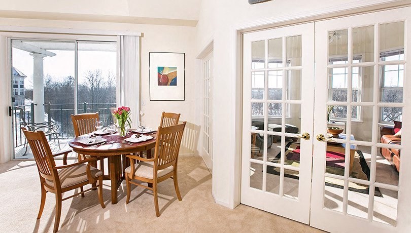 a dining room with french doors leading to a balcony