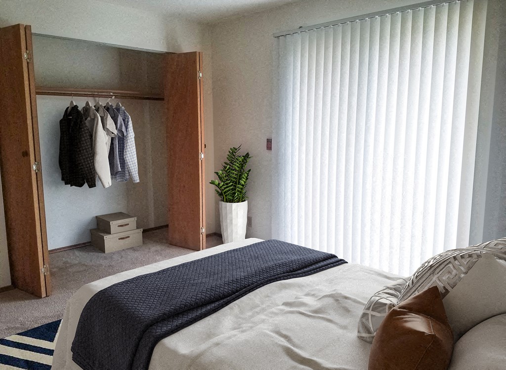 a bedroom with a bed and a closet with clothes hanging