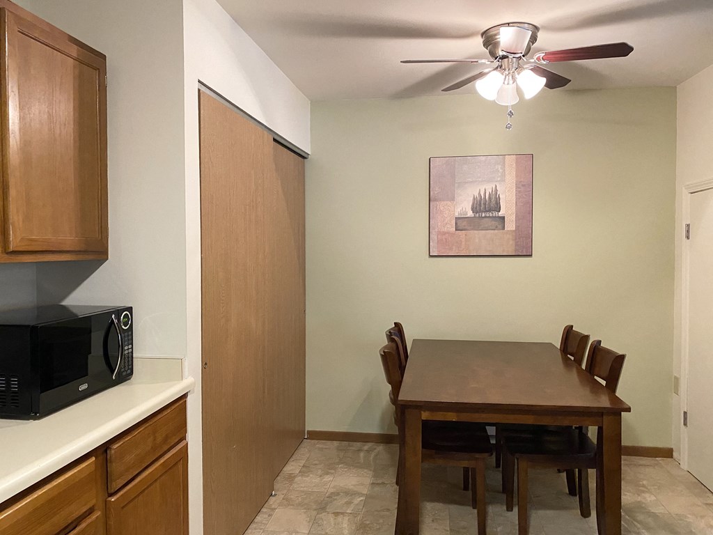 a dining room with a table and a kitchen with a microwave
