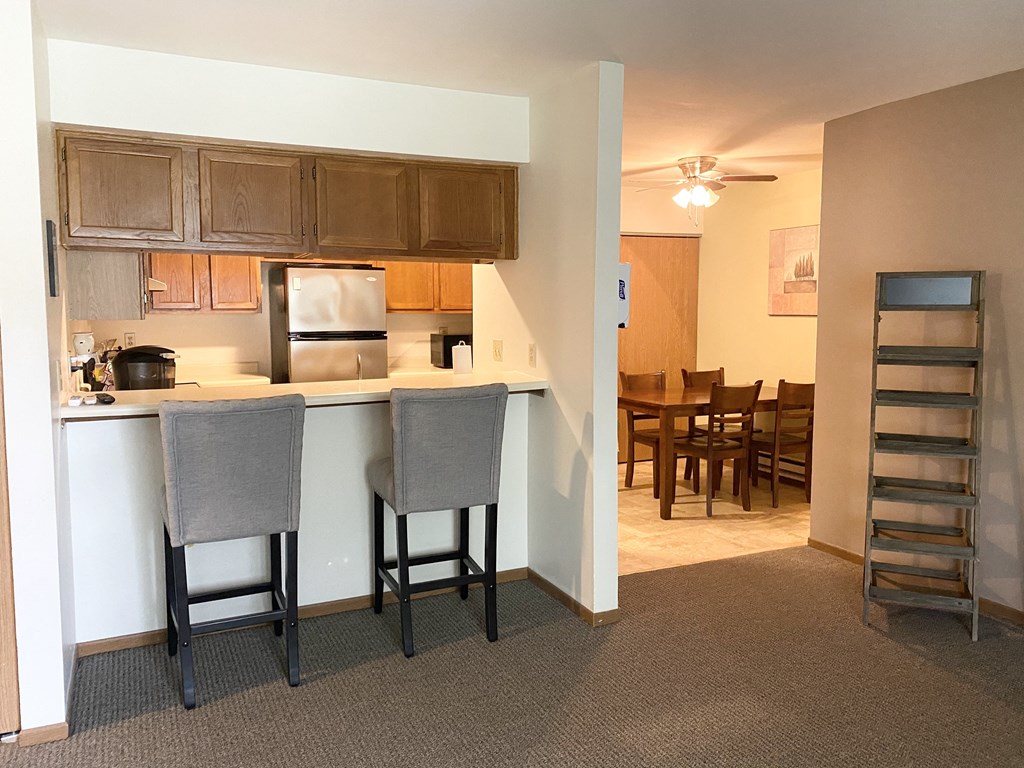 a kitchen with a bar and a dining room with a table and chairs