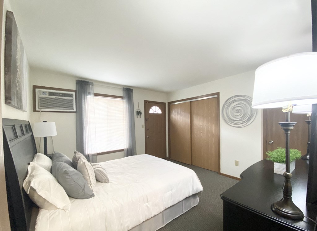 a bedroom with a large bed and a dresser with a lamp