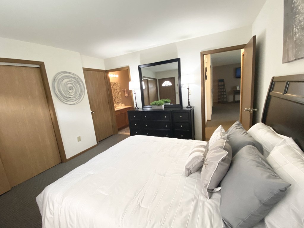 a bedroom with a bed and a dresser and a bathroom