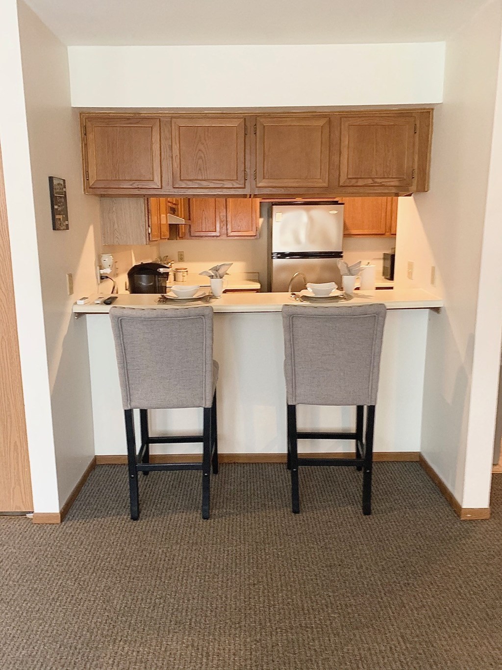 an empty kitchen with two chairs in front of a counter