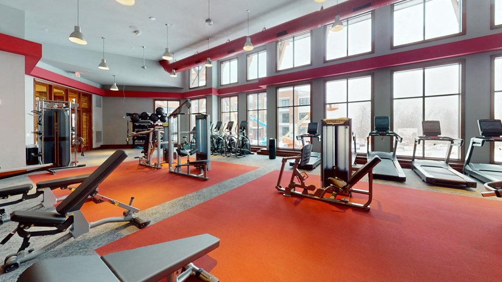 A gym with a red floor and various exercise equipment.