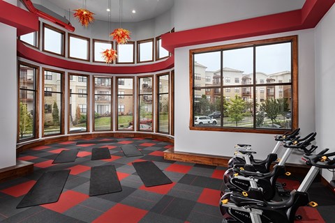 A gym with a row of stationary bikes and a checkered floor.