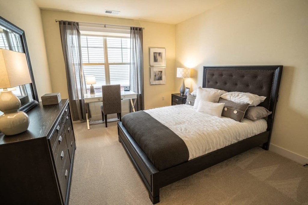 a bedroom with a bed and a desk and a window