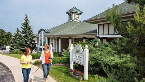 two women walking a dog in front of a building